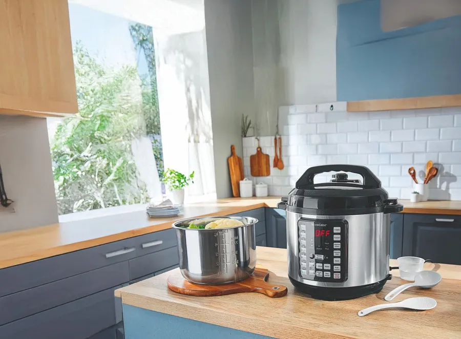 Panier vapeur rempli de légumes à côté d'un autocuiseur électrique