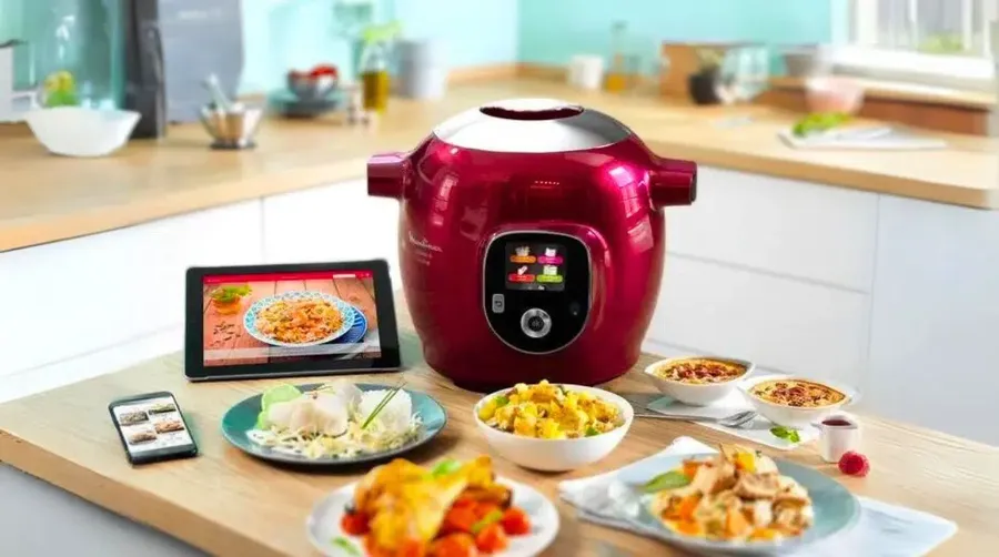 Multicuiseur connecté avec tablette affichant des recettes, entouré de plats