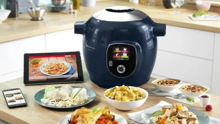 Plats variés en sauce servis à table à côté d'un multicuiseur électrique